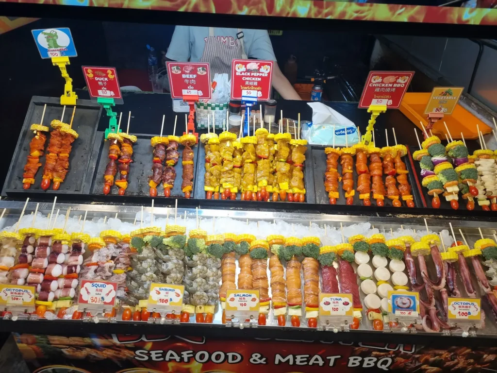 spiedini di carne cotti al momento su griglia in uno street food asiatico